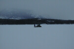 Team members near their snowmobiles in the snow.