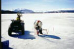 Alan Hildebrand cutting into ice with a chain saw.